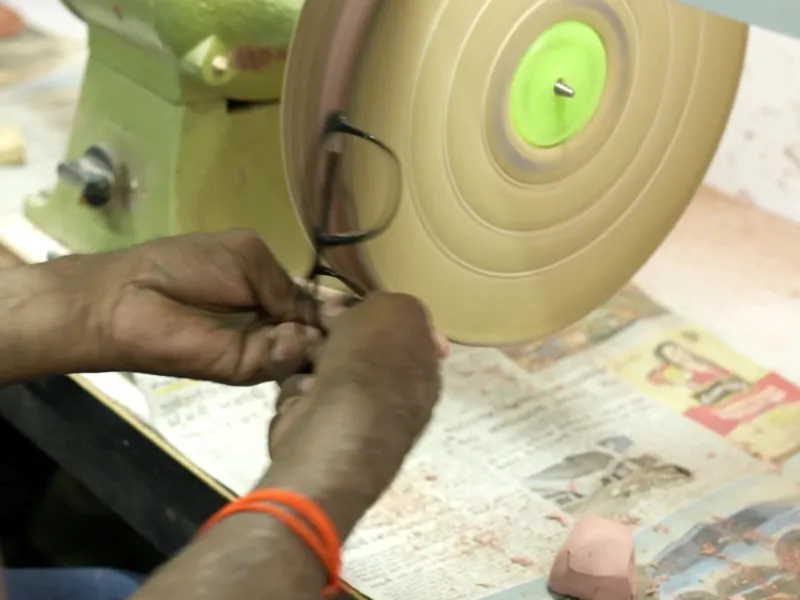 Craftsman hand finishing the edge of an acetate frame front on a polishing wheel